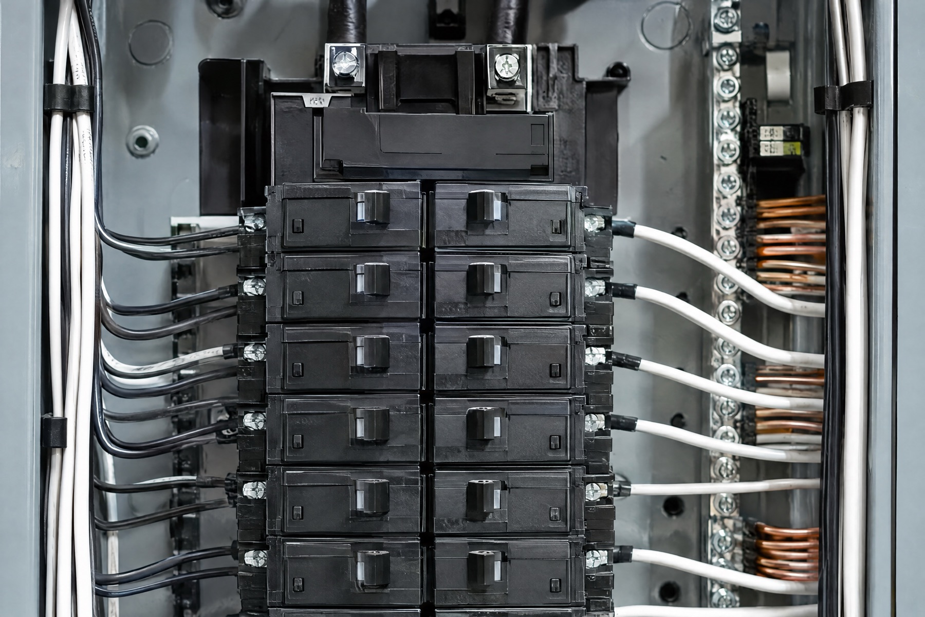 A new electrical panel with neat rows of breakers and white cables dressed down each side
